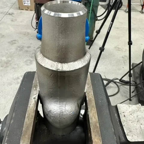 Machined cylindrical steel part held in shop vise